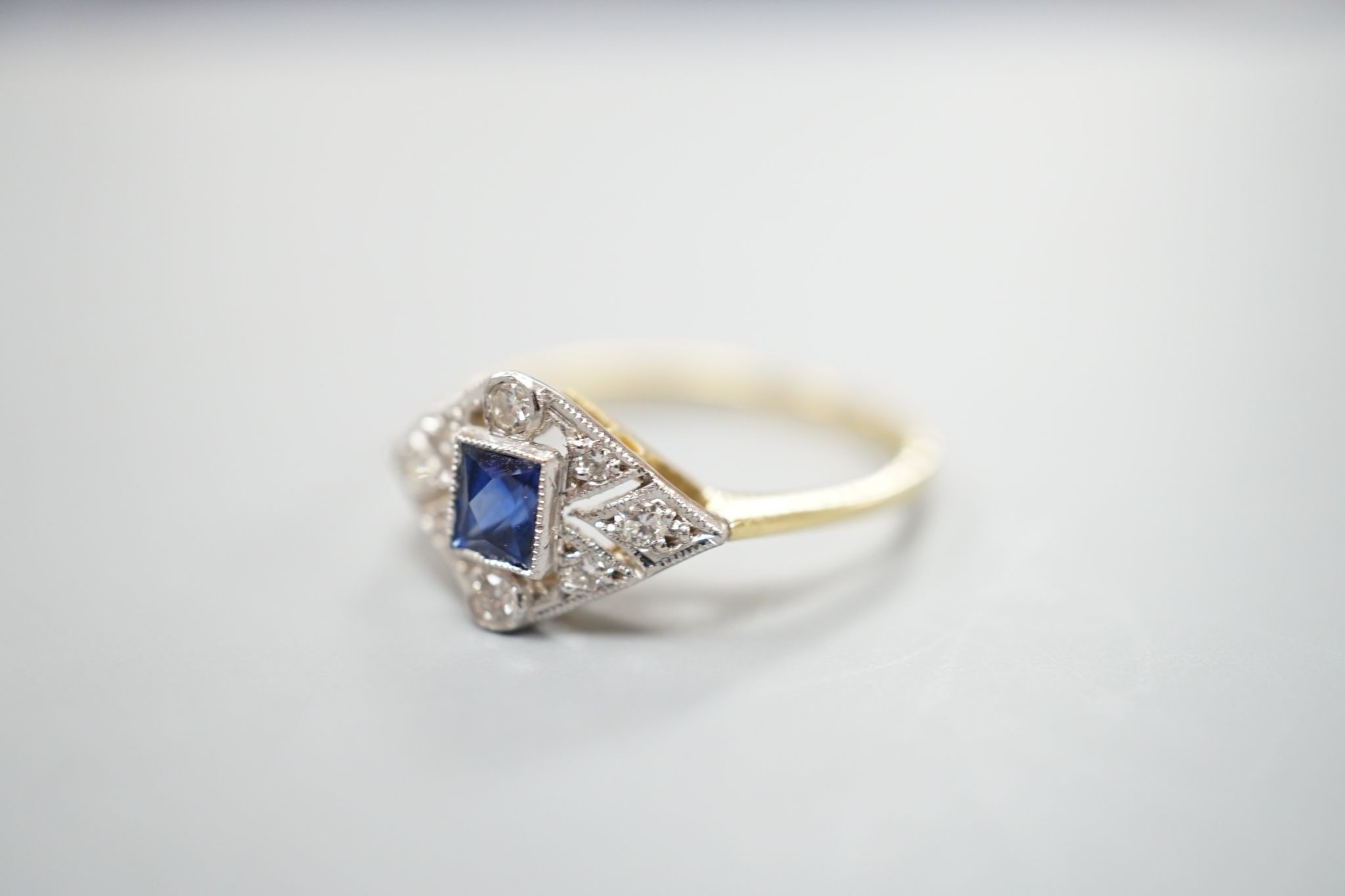 A 1920's 18ct, sapphire and diamond set shaped cluster ring, size N, gross weight 2.5 grams.